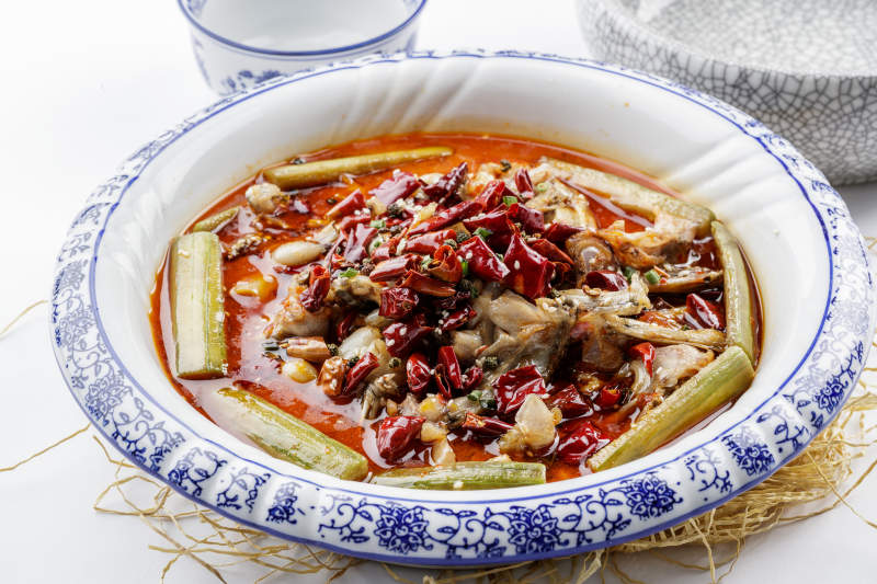 青花瓷盤裝的湘味饞嘴蛙擺放在白色底板上