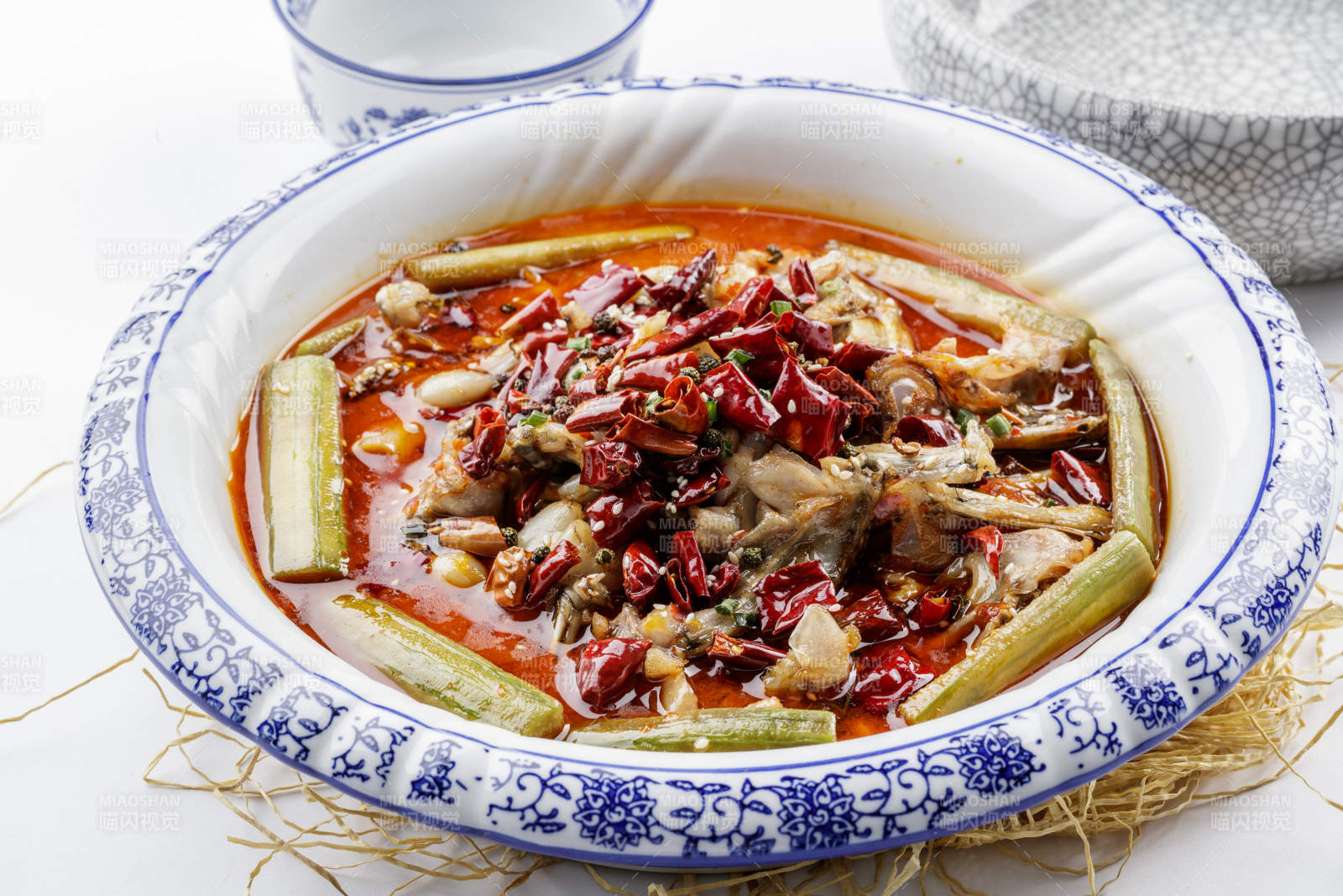 青花瓷盤裝的湘味饞嘴蛙擺放在白色底板上