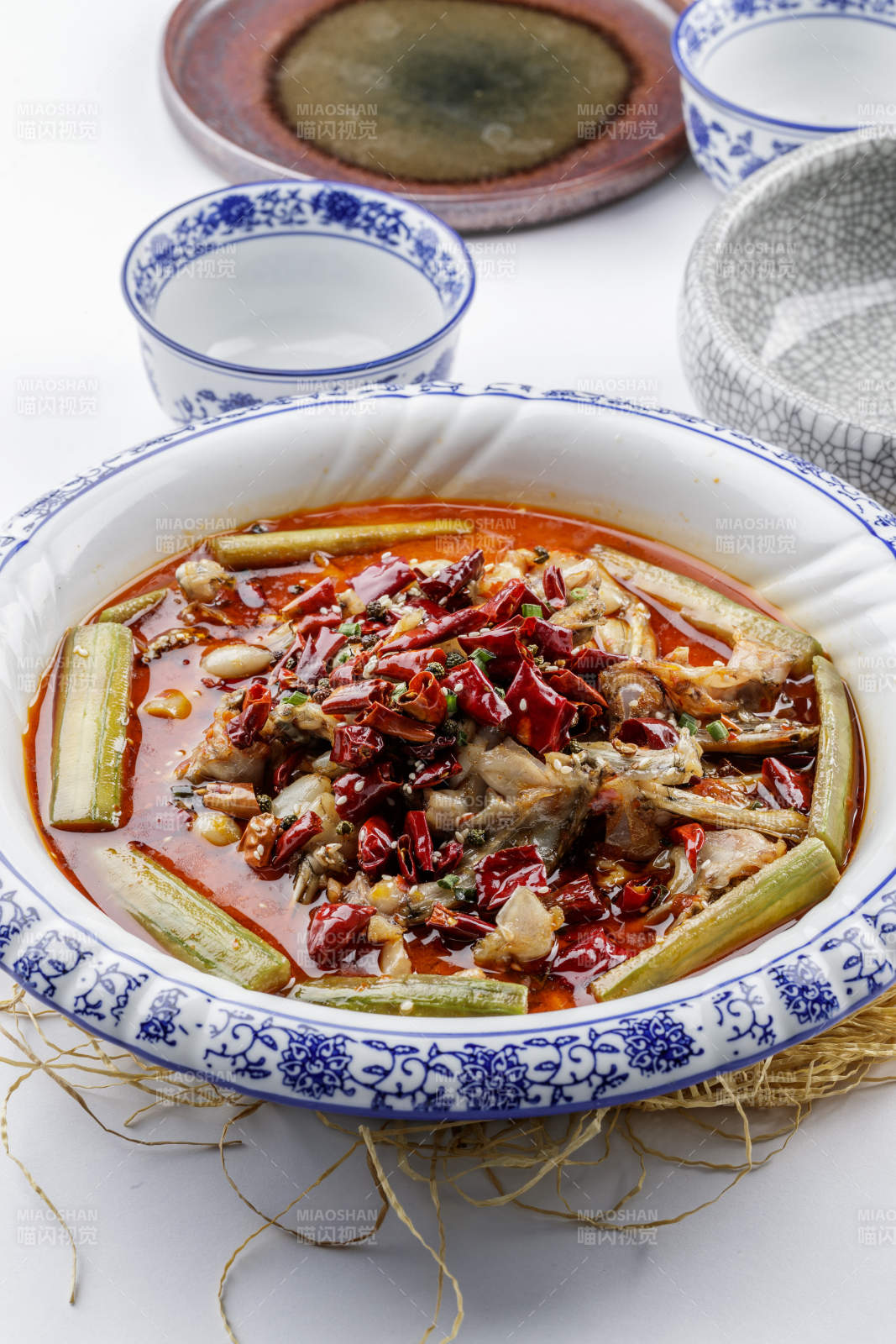 青花瓷盤裝的湘味饞嘴蛙擺放在白色底板上