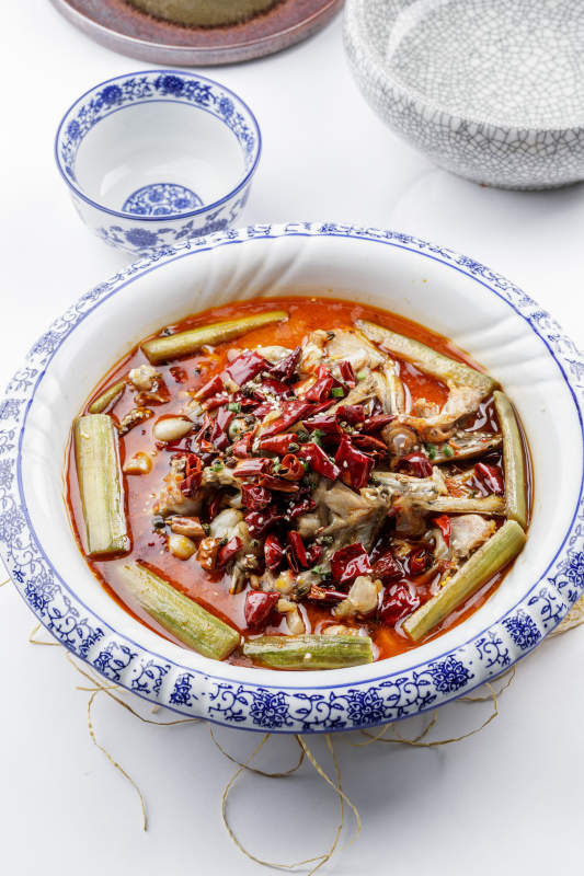 青花瓷盤裝的湘味饞嘴蛙擺放在白色底板上