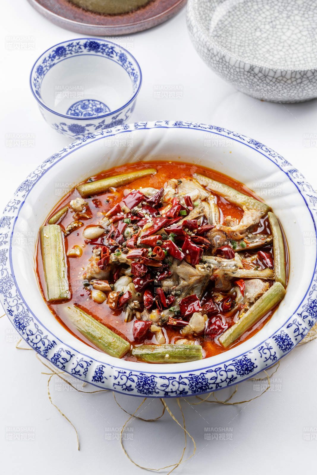 青花瓷盤裝的湘味饞嘴蛙擺放在白色底板上