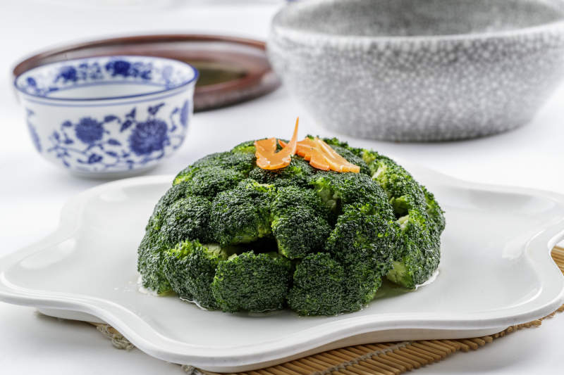 白色梅花瓷盘装的白灼西蓝花摆放在寿司帘上图片