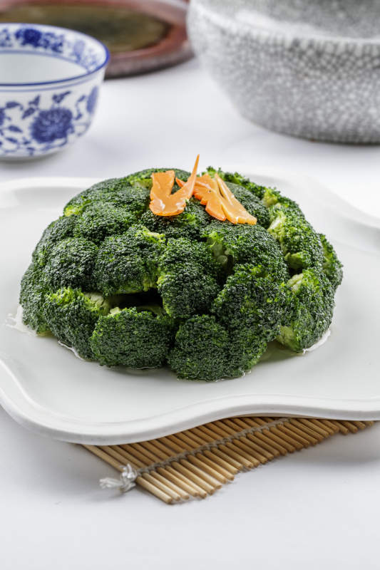 白色梅花瓷盘装的白灼西蓝花摆放在寿司帘上图片