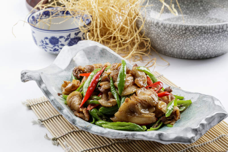 青瓷盘装的湘味小炒肉摆放在寿司帘上