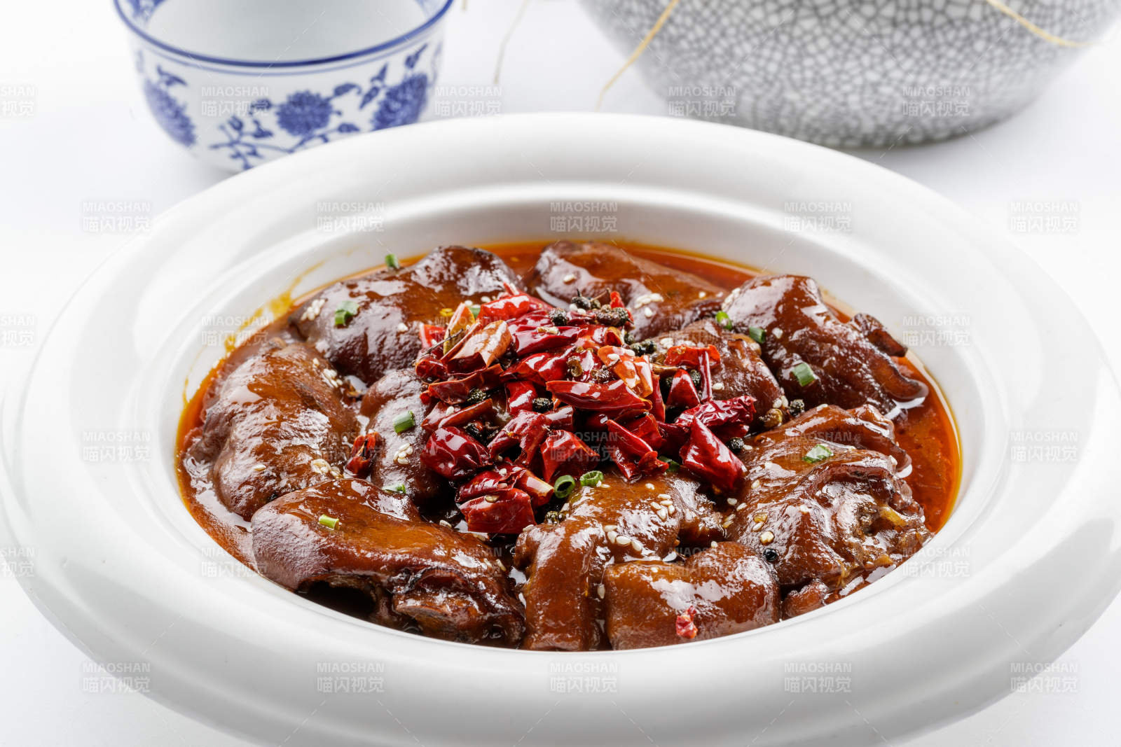 白色圆盘装的香辣猪蹄摆放在白色背景上