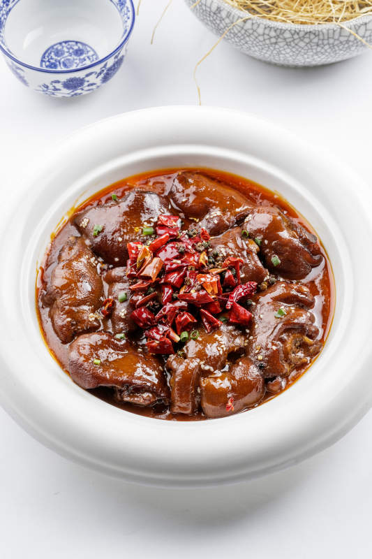 白色圆盘装的香辣猪蹄摆放在白色背景上