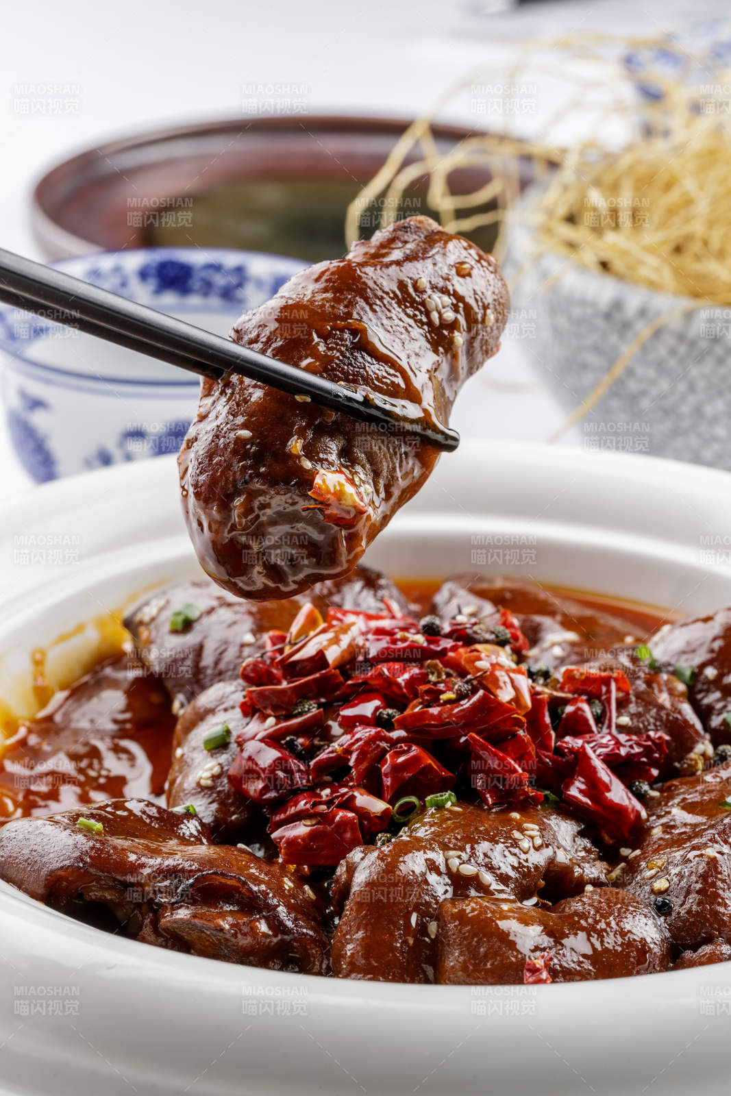 白色圆盘装的香辣猪蹄摆放在白色背景上