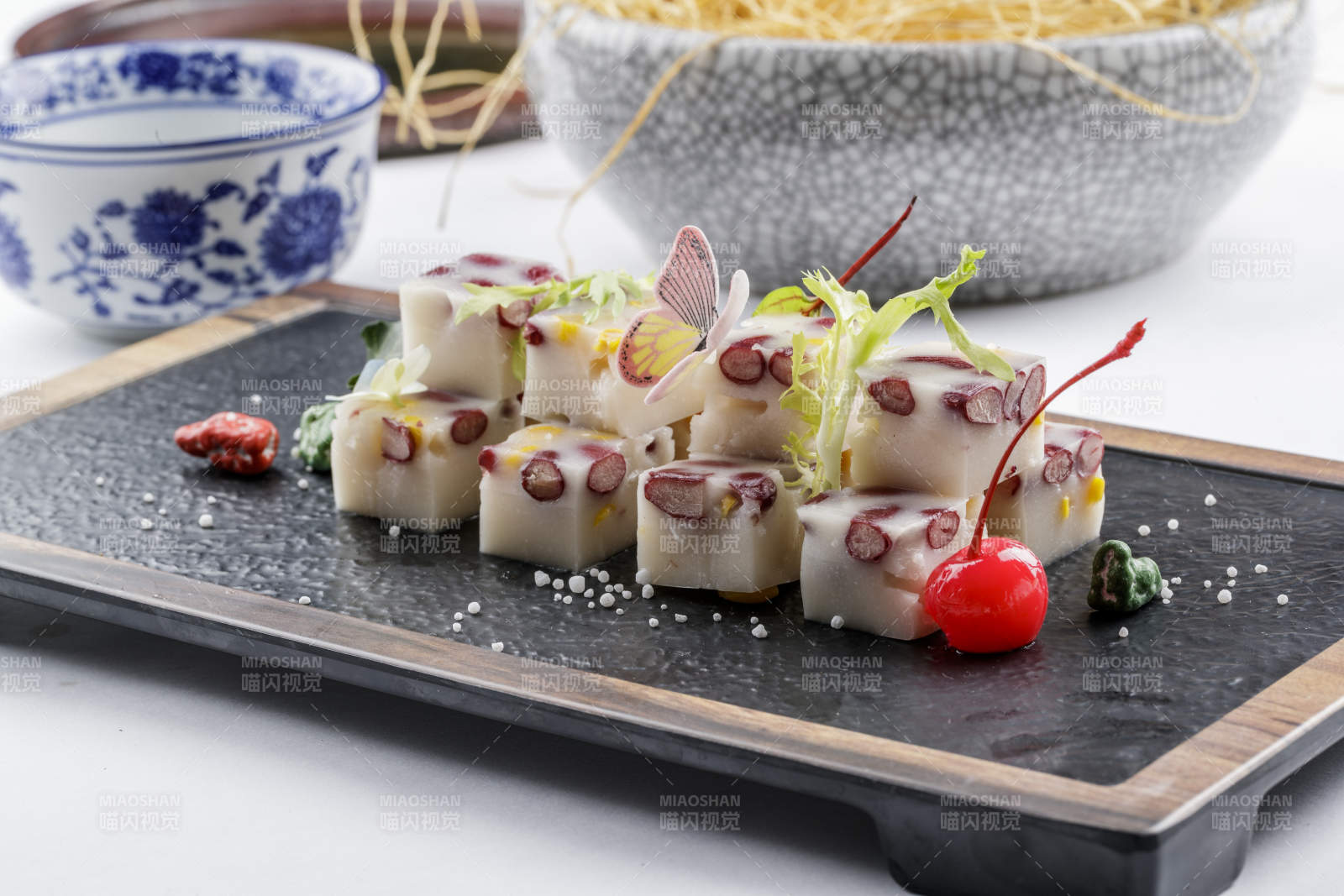 黑色石盘装的酸奶红豆糕摆放在白色背景上