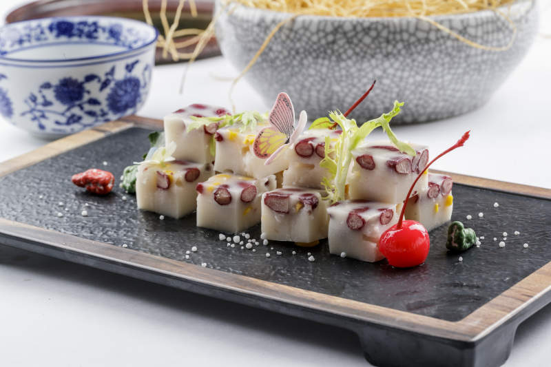 黑色石盘装的酸奶红豆糕摆放在白色背景上