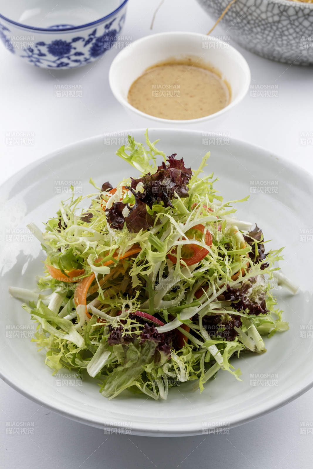 青色瓷盘装的呛拌苦菊摆放在白色背景上-摄影图