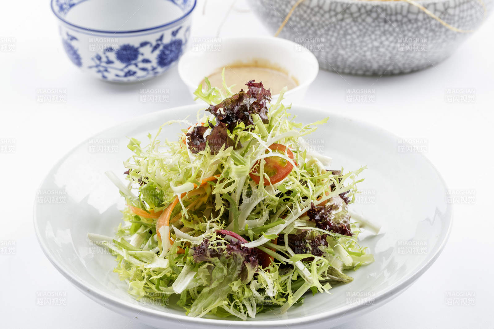 青色瓷盘装的呛拌苦菊摆放在白色背景上-摄影图