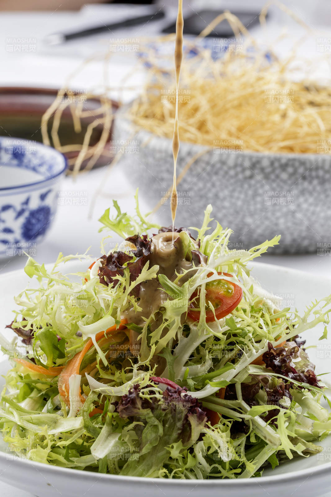 青色瓷盘装的呛拌苦菊摆放在白色背景上-摄影图