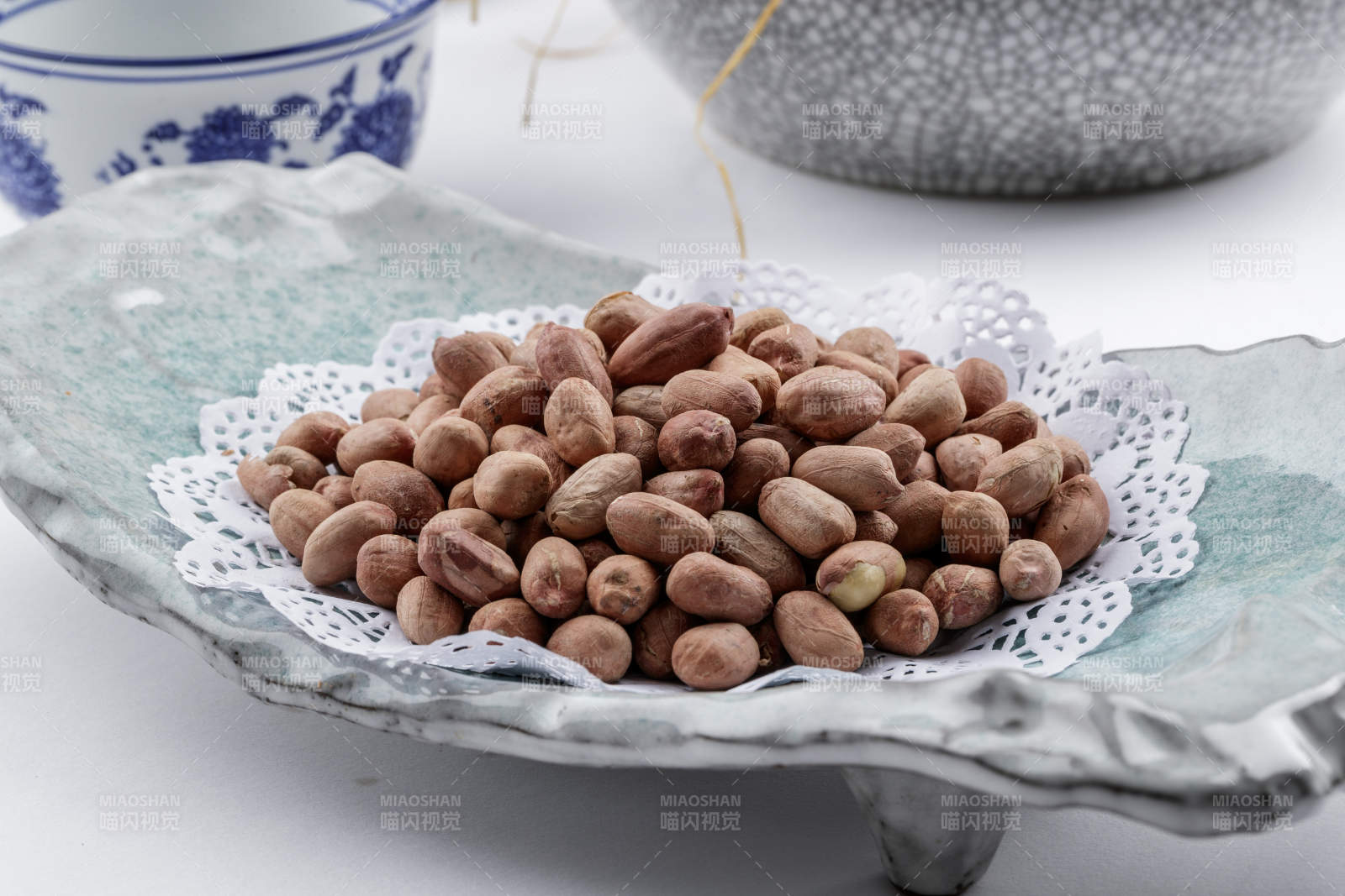 青瓷盘装的有机花生米摆放在白色背景上