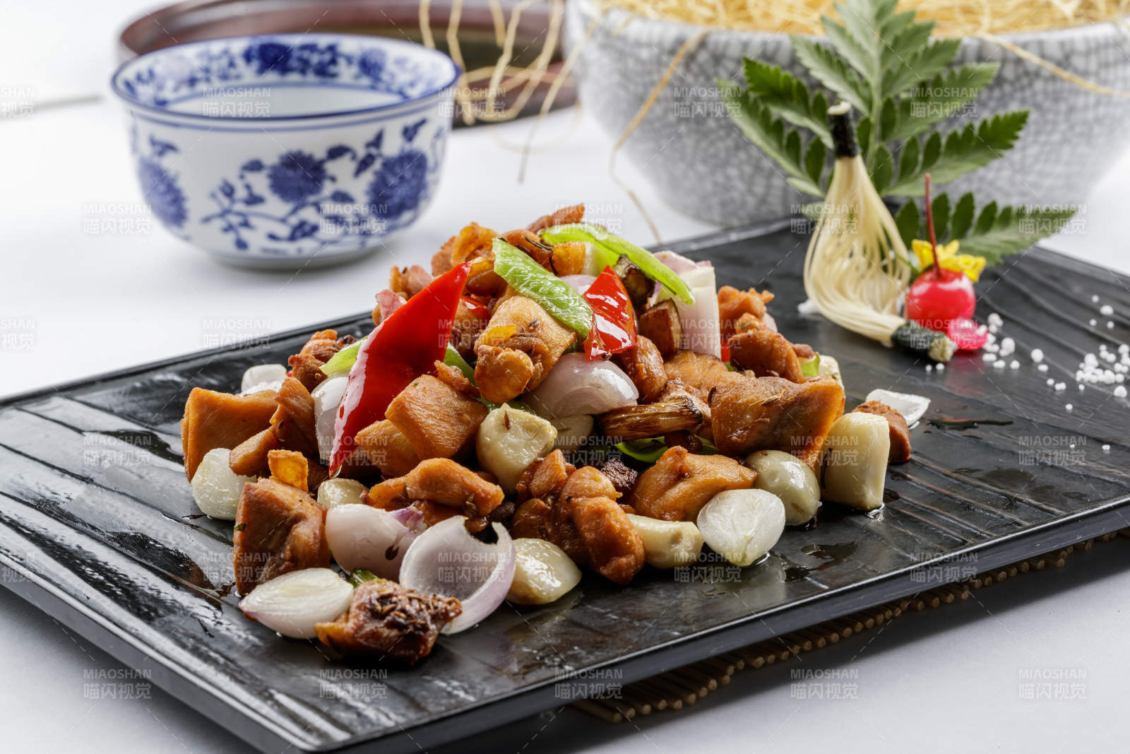 黑色石盤裝的毛蒜燒豬腩肉擺放在白色背景上