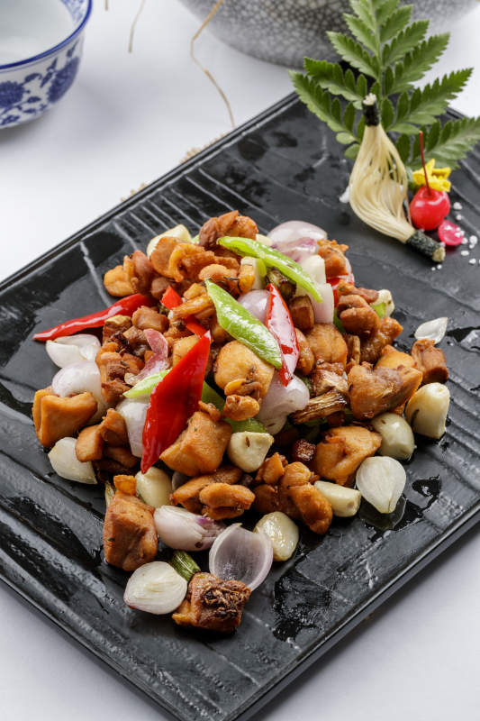 黑色石盤裝的毛蒜燒豬腩肉擺放在白色背景上