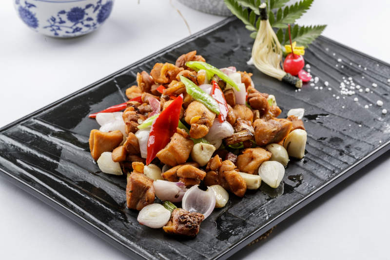 黑色石盤裝的毛蒜燒豬腩肉擺放在白色背景上