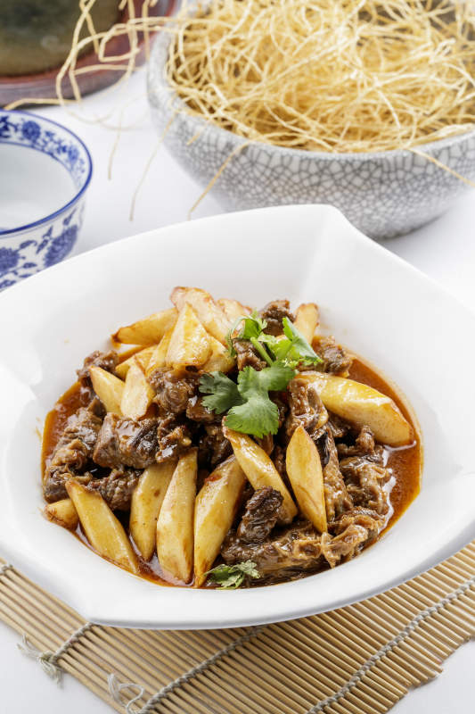 方形瓷盘装的长山药炖牛腩摆放在寿司帘上