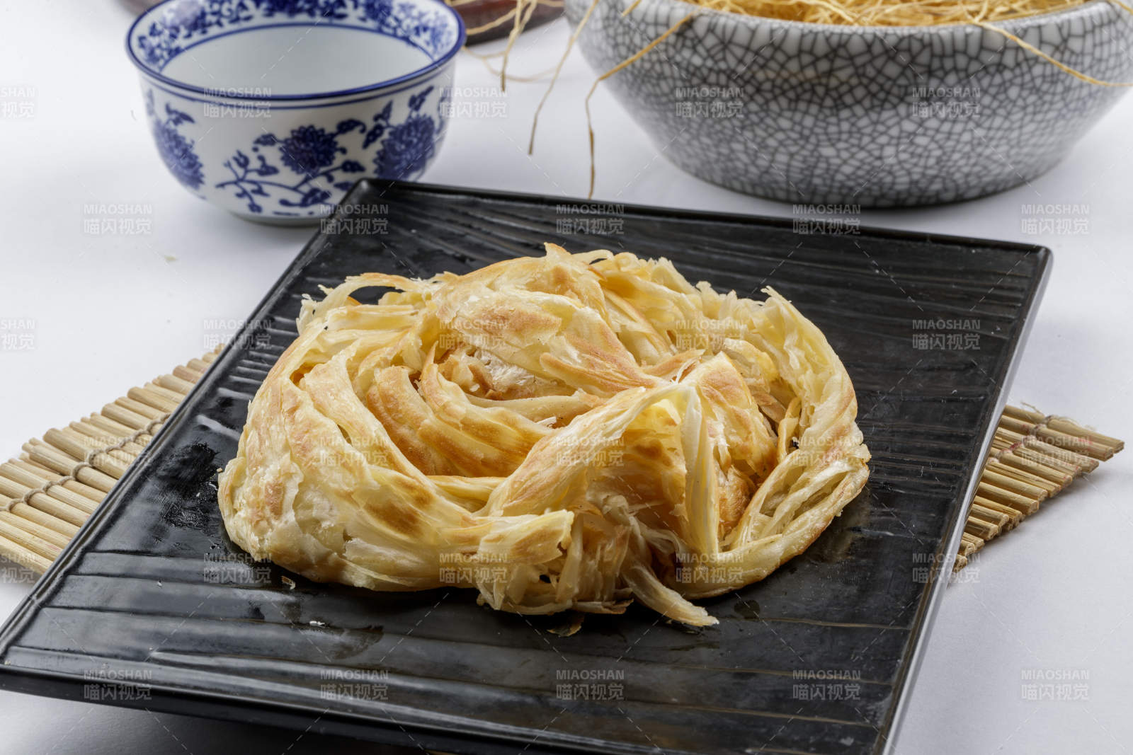 黑色石盘装的一窝丝摆放在寿司帘上图片