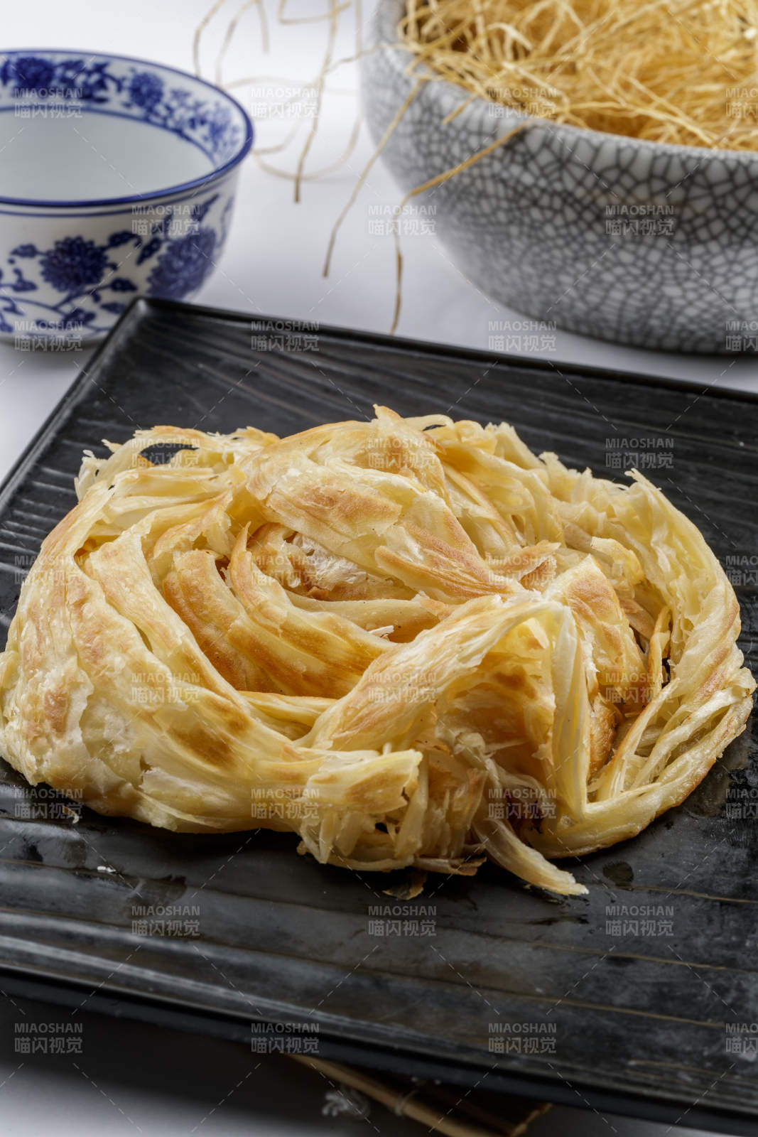 黑色石盘装的一窝丝摆放在寿司帘上-摄影图