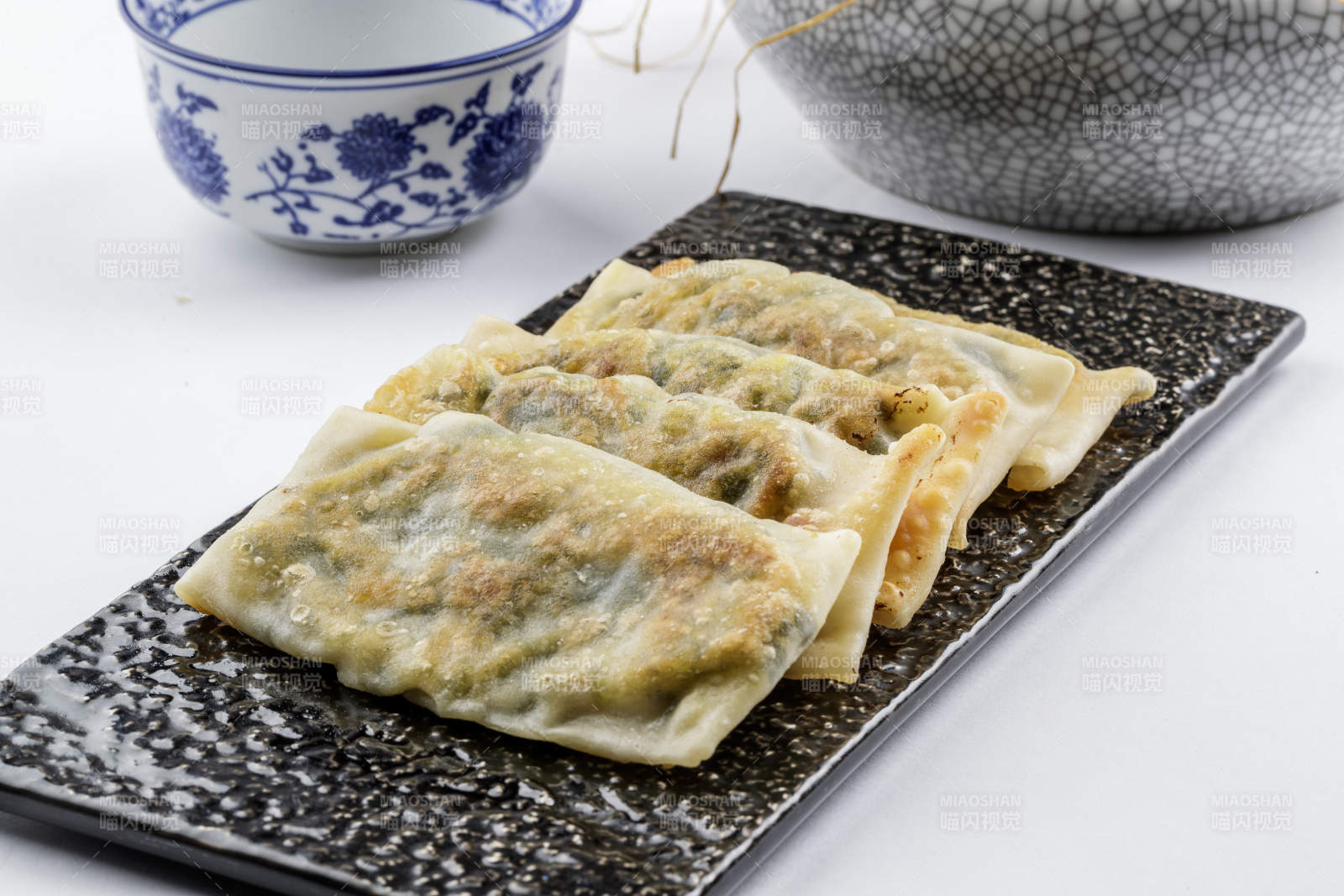 黑色磁盤裝的香酥韭菜盒子擺放在白色背景上