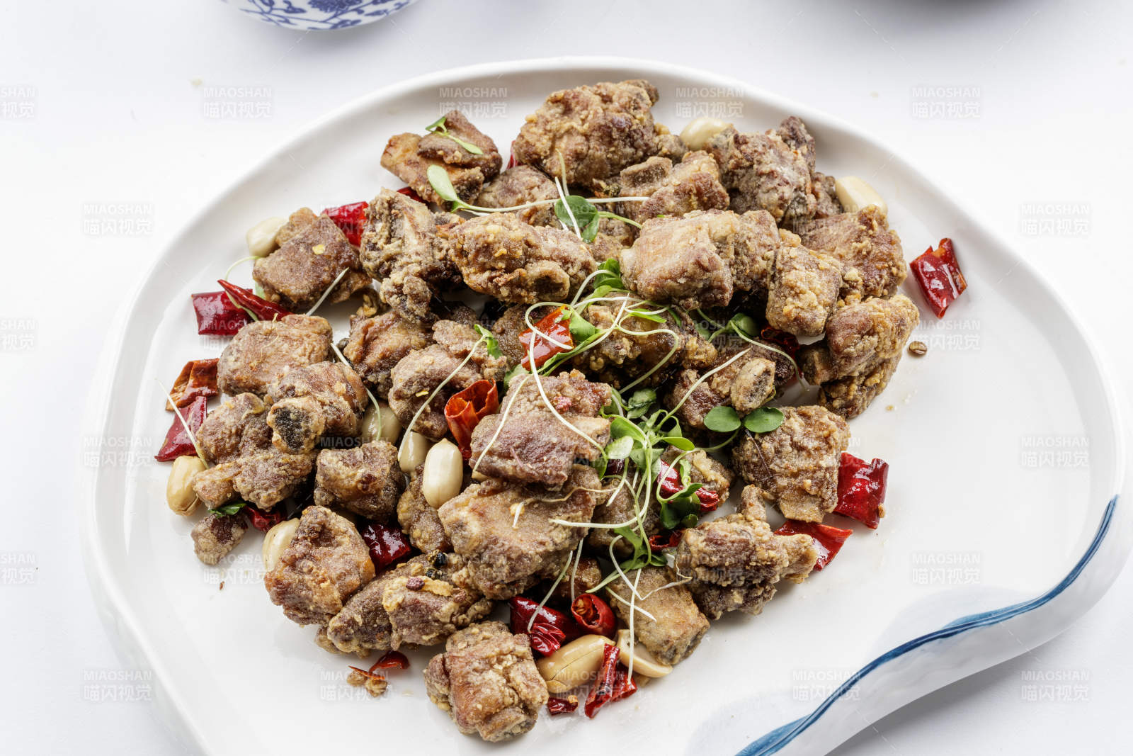 异形瓷盘装的香炸小排骨摆放在白色背景上