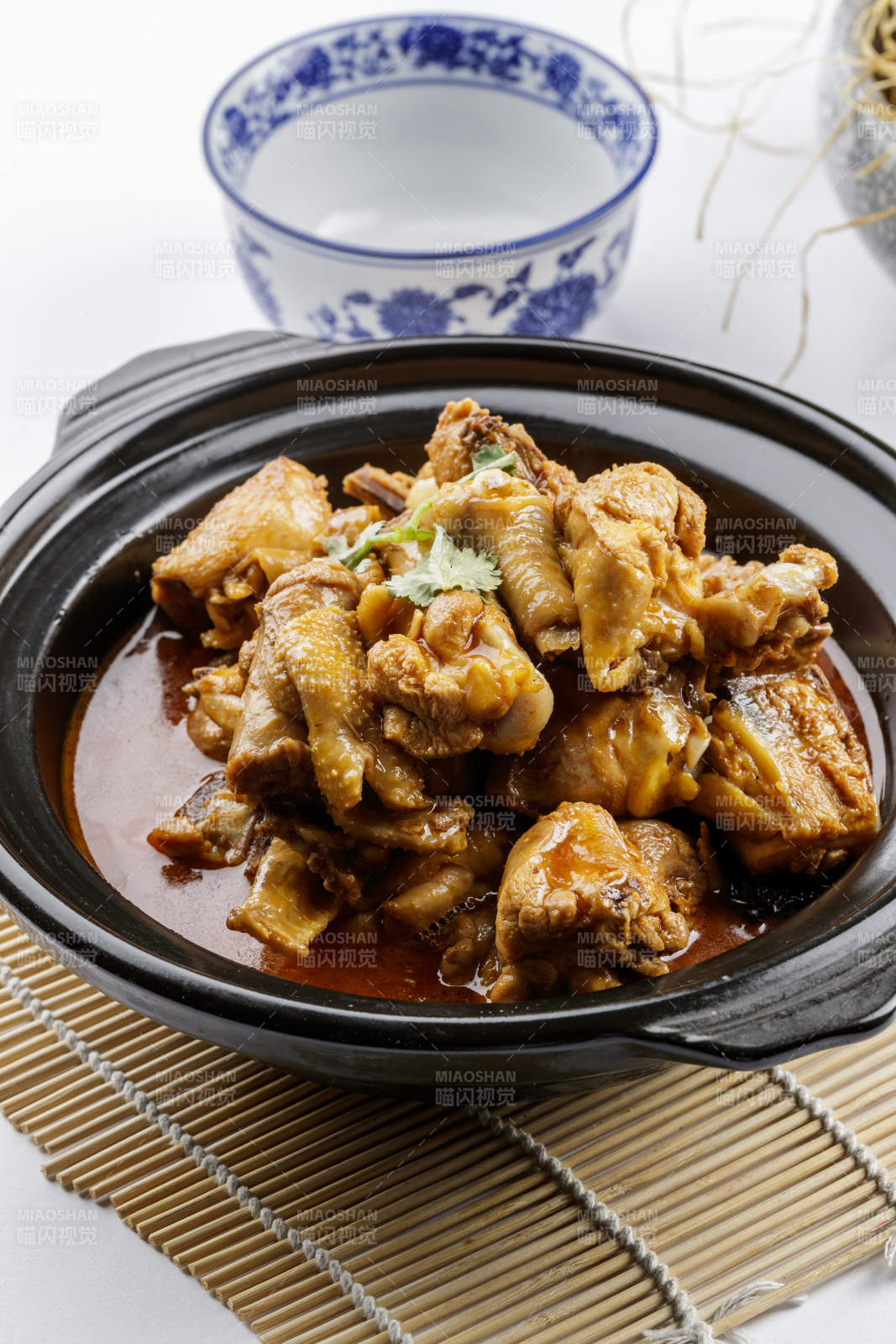 黑色砂锅装的文火散养鸡摆放在寿司帘上图片