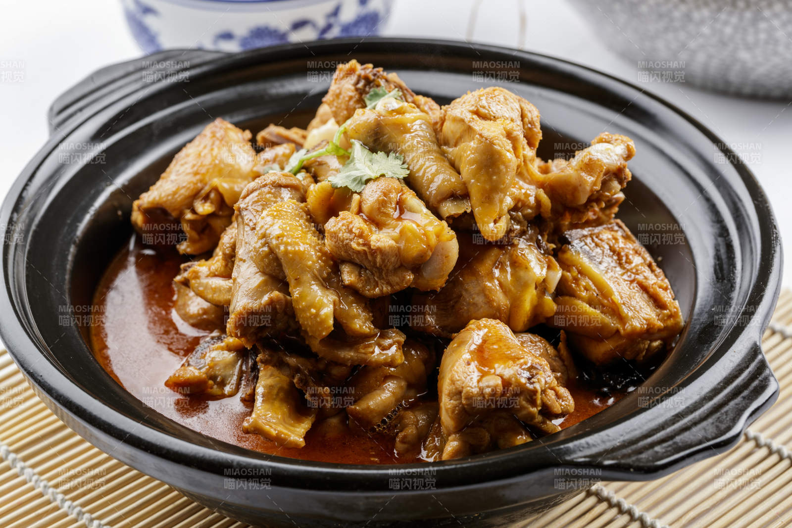 黑色砂锅装的文火散养鸡摆放在寿司帘上图片