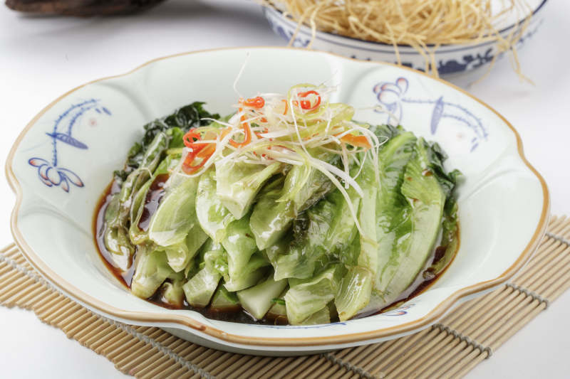 壽司簾上的復古瓷盤裝的耗油菜心