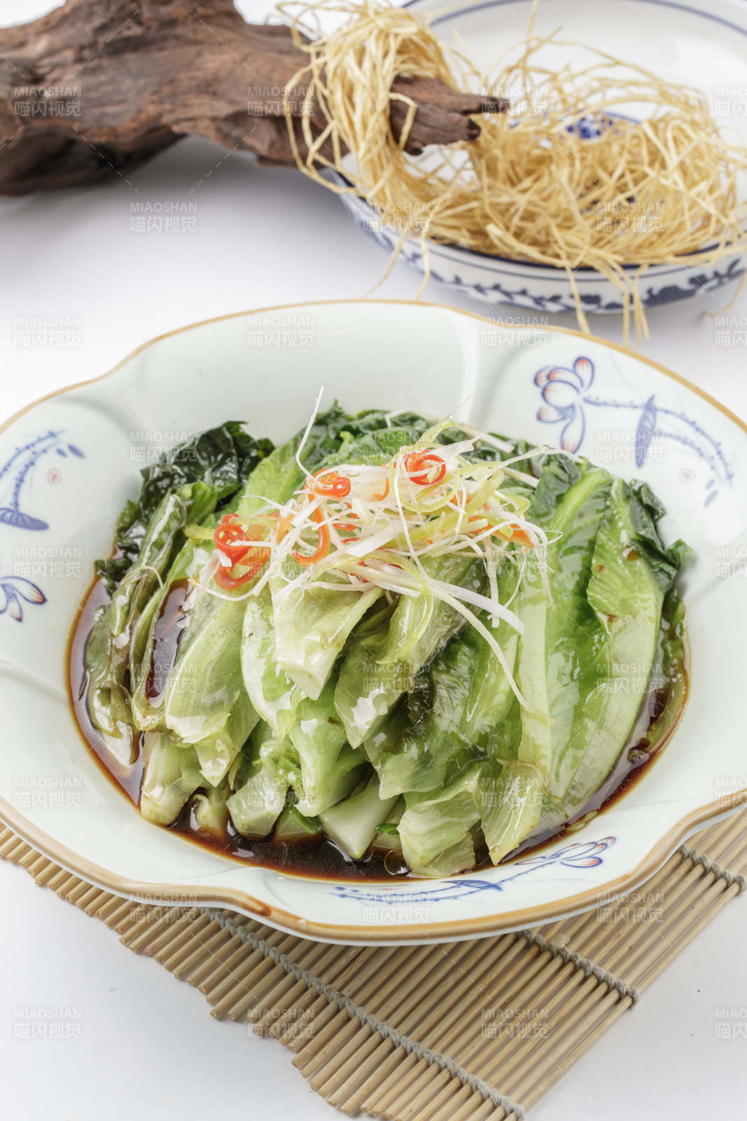 壽司簾上的復古瓷盤裝的耗油菜心