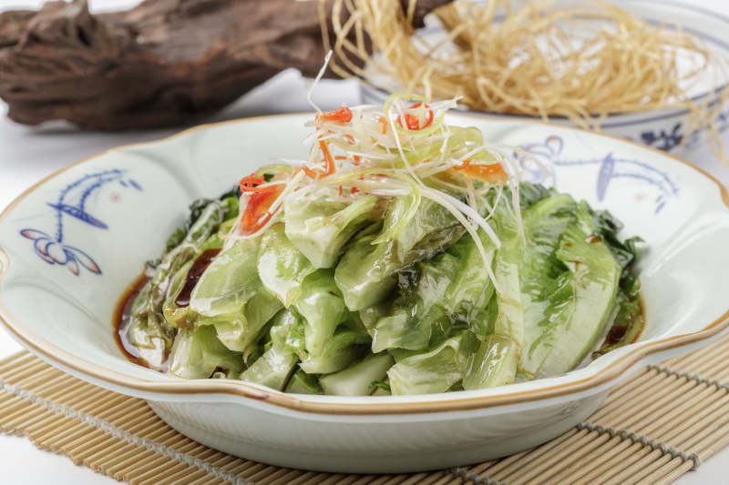 壽司簾上的復古瓷盤裝的耗油菜心