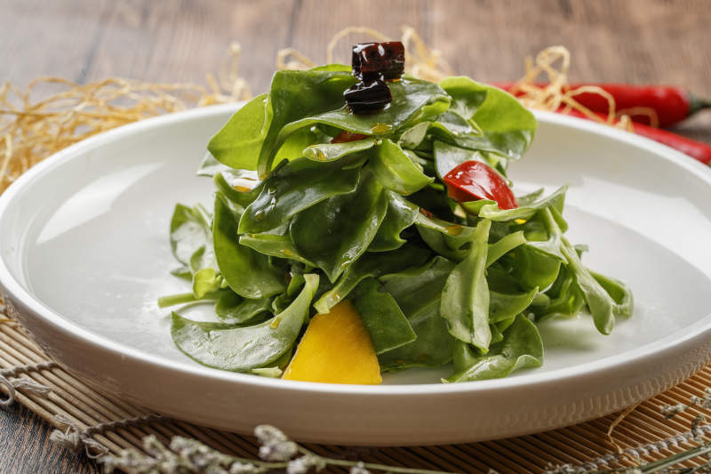 寿司帘上的圆瓷盘装的凉拌穿心莲