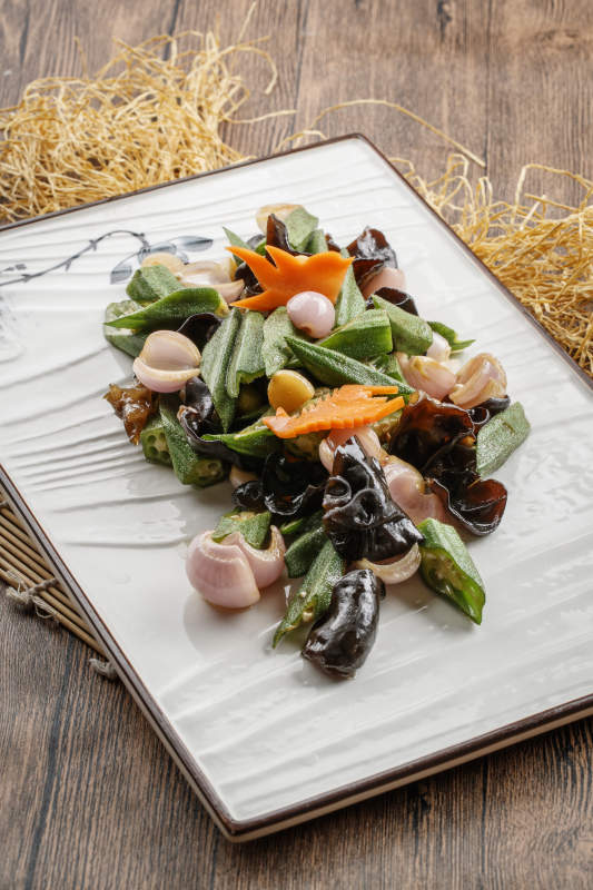 木质底纹上的长瓷盘装的木耳洋葱炒秋葵