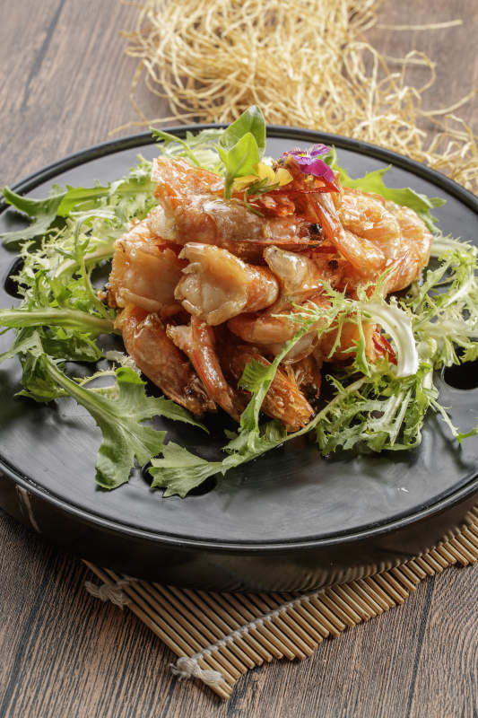 木质底纹上的黑石盘装的油炸大明虾