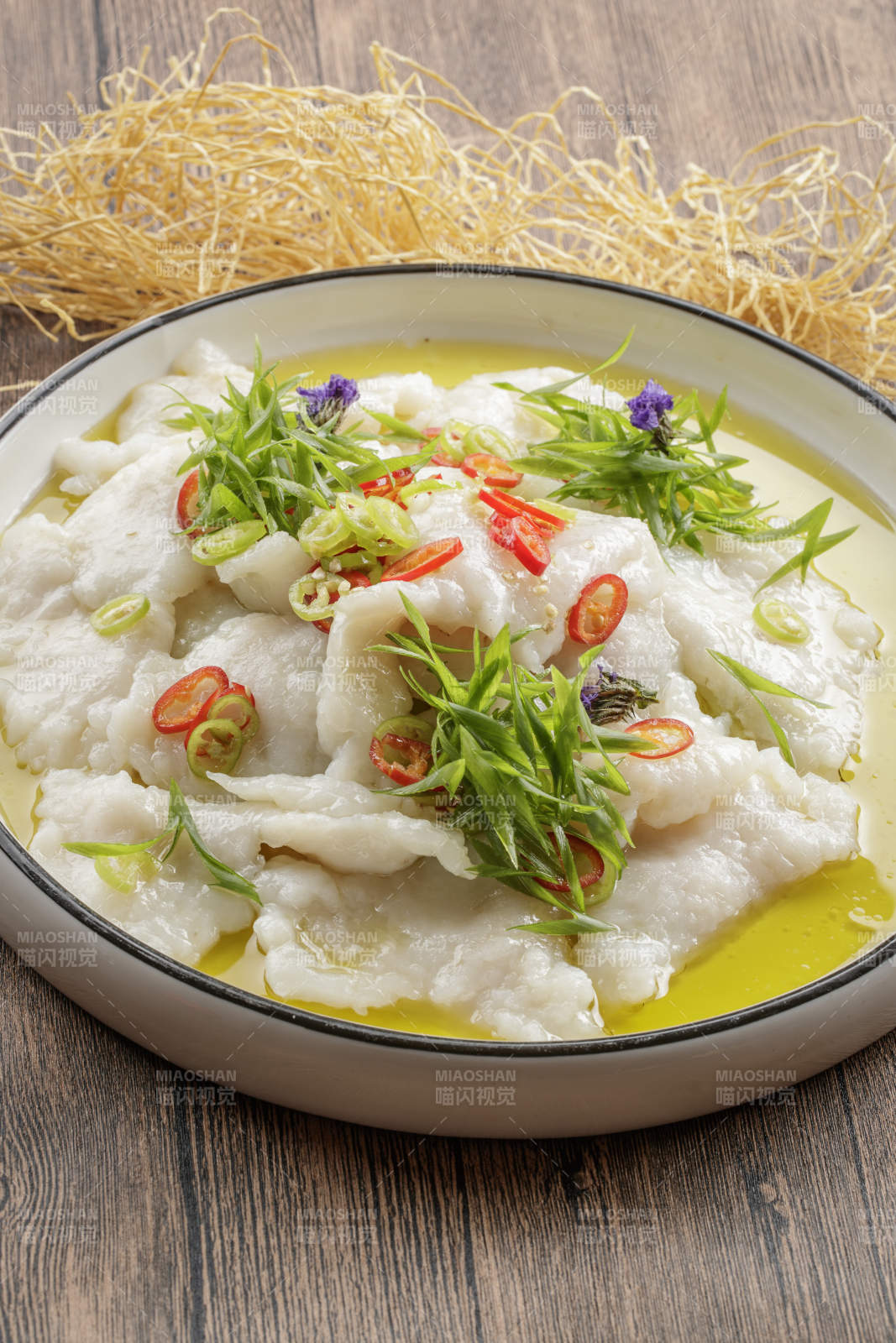 木质底纹上的圆瓷盘装的酸汤龙利鱼片