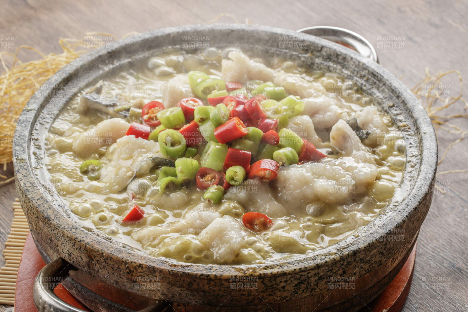 红木托盘上的石锅装的湘味沸腾鱼