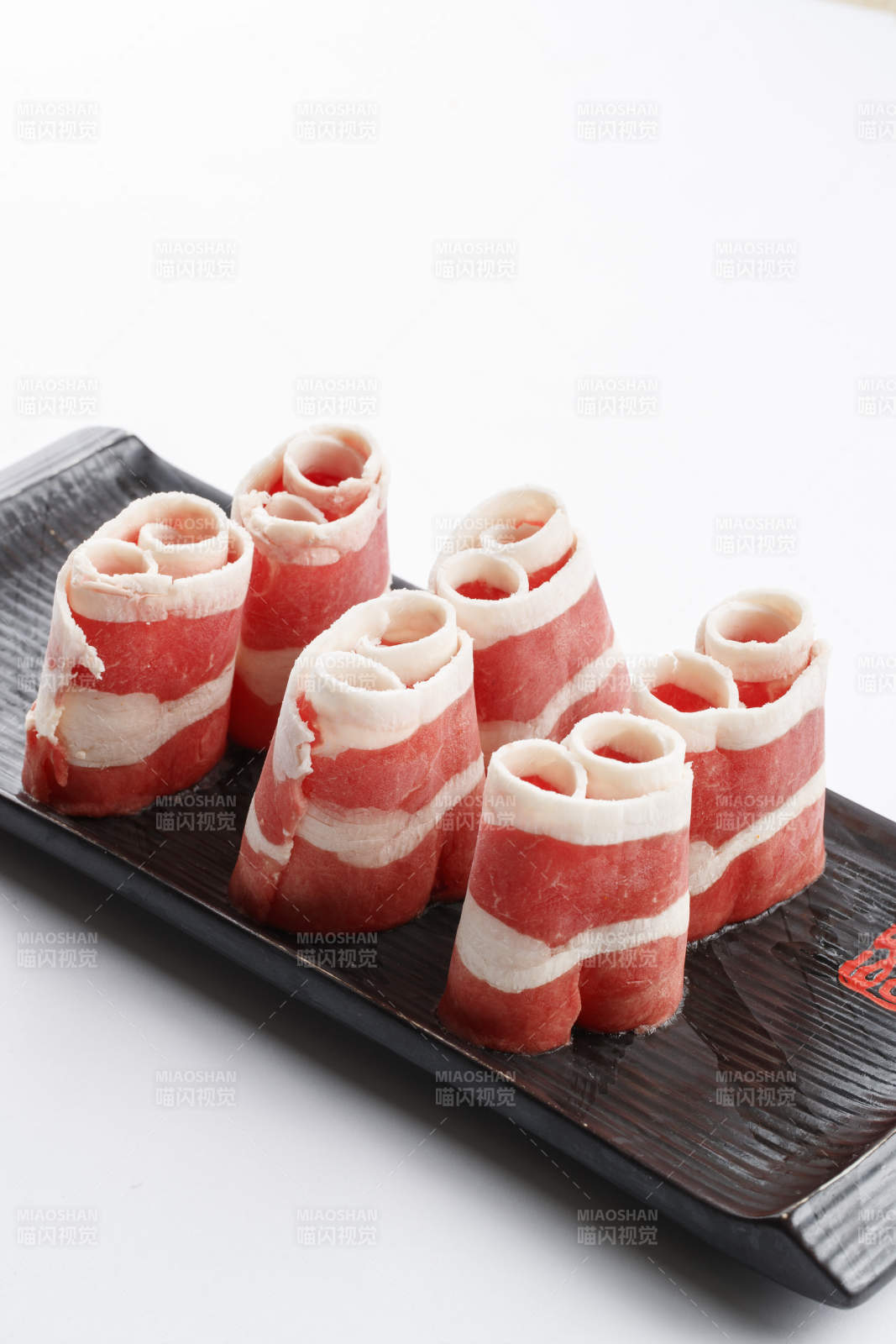 長方形黑色瓷盤裝的羊五花卷