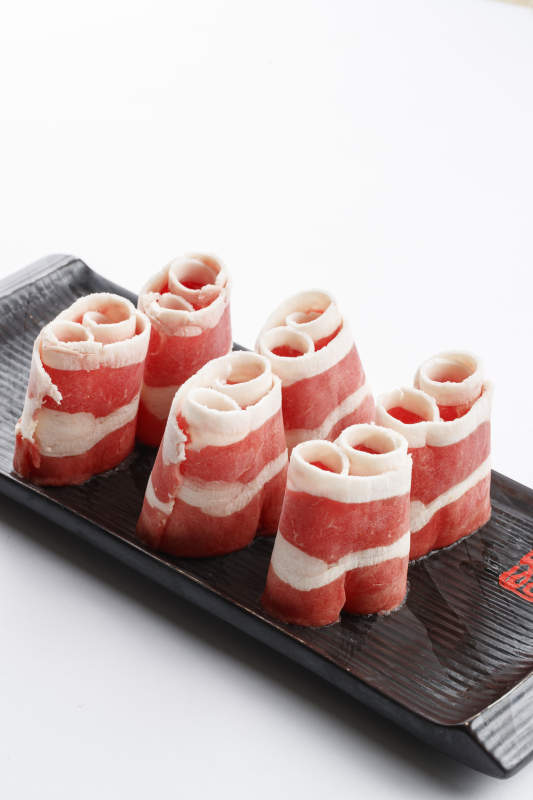 長方形黑色瓷盤裝的羊五花卷