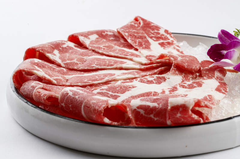 铺满碎冰的圆形瓷盘装的雪花肥牛片