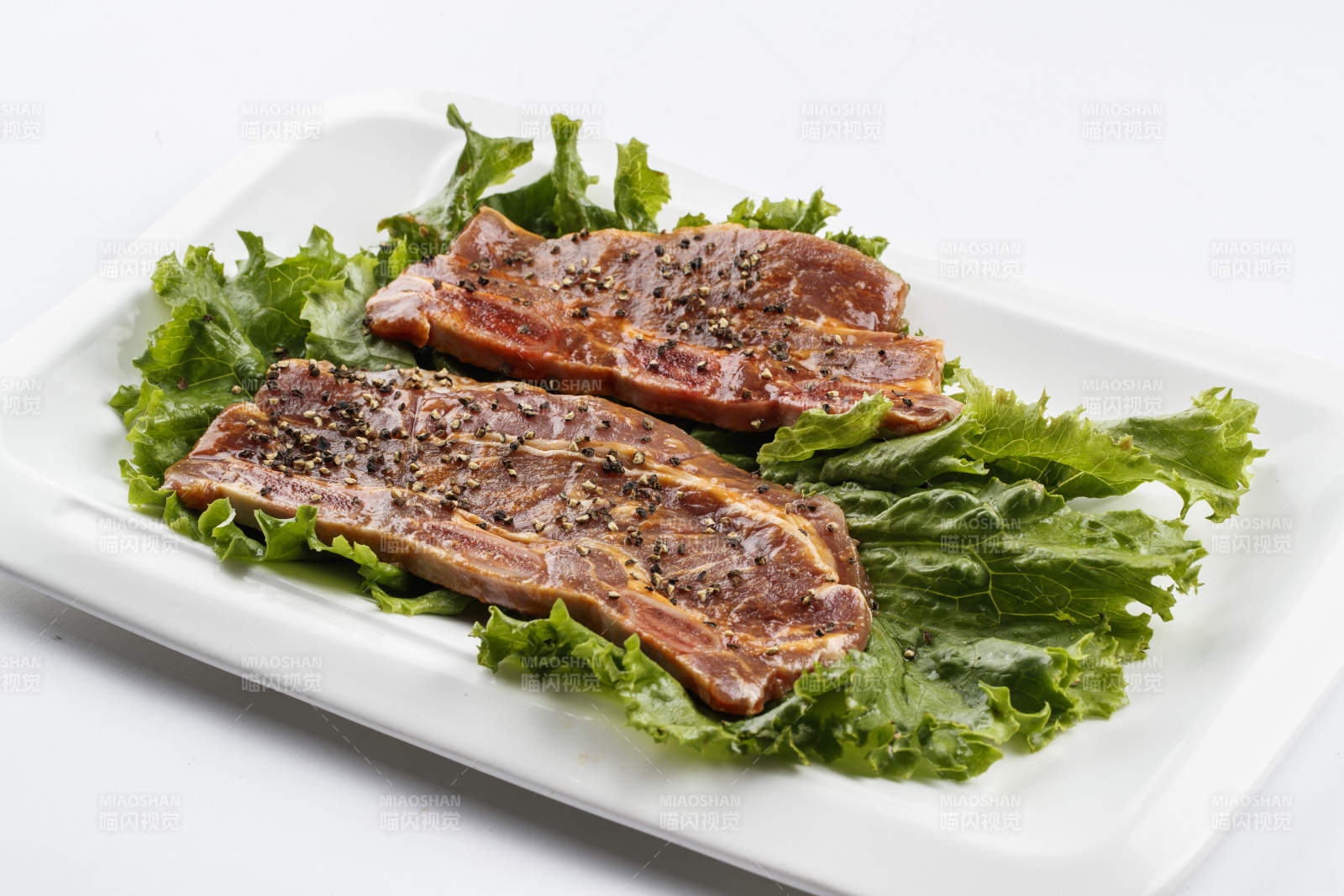 長方形白瓷盤裝的黑胡椒腌制牛排肉