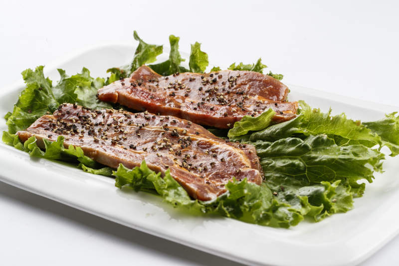 長(zhǎng)方形白瓷盤(pán)裝的黑胡椒腌制牛排肉