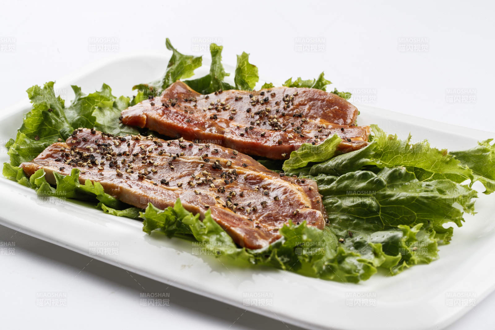 長方形白瓷盤裝的黑胡椒腌制牛排肉