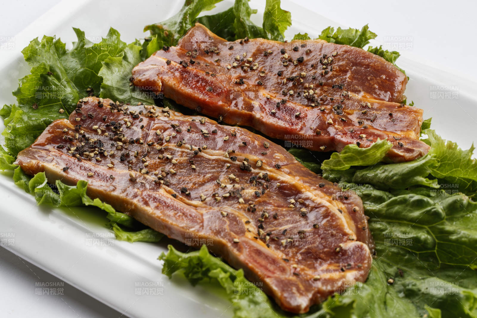 長方形白瓷盤裝的黑胡椒腌制牛排肉