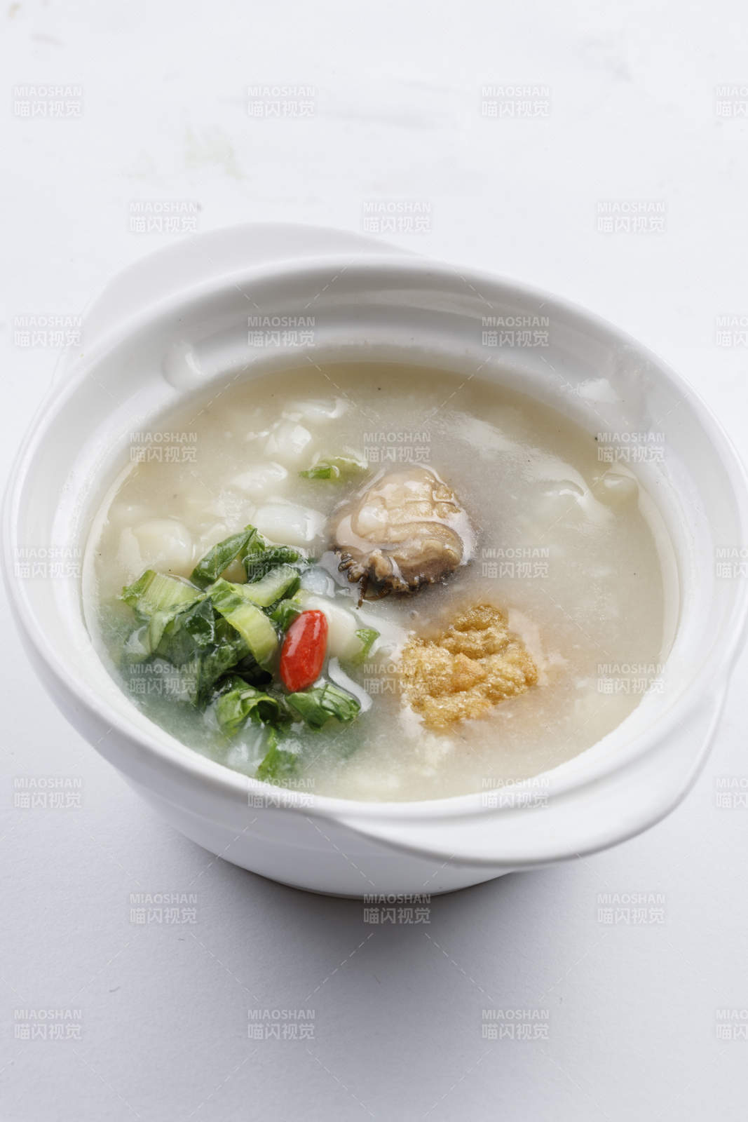 白色瓷碗裝的鮮鮑魚小白菜粥