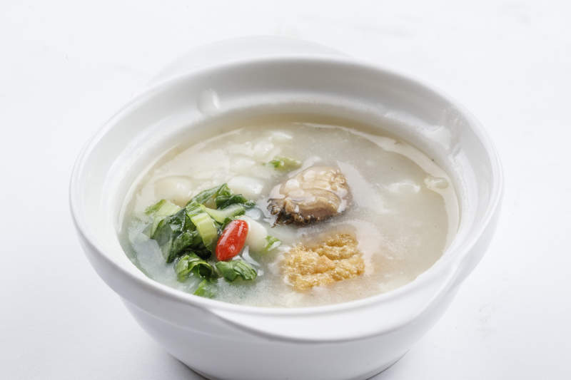 白色瓷碗裝的鮮鮑魚小白菜粥