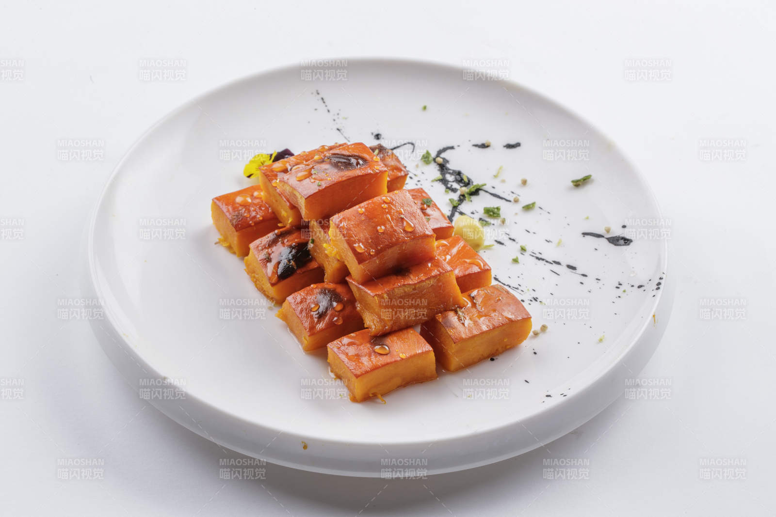 青瓷盘装的蜂蜜焗南瓜摆放在白色背景上
