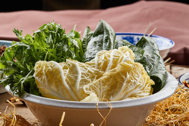 白色瓷盆装的火锅涮菜茼蒿白菜菠菜