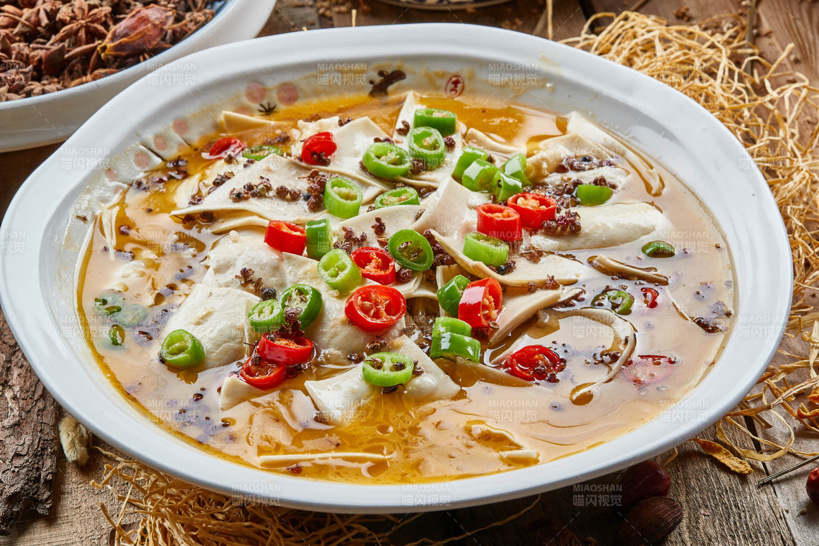 青瓷汤盆装的酸汤黄喉摆放在陈旧木板上