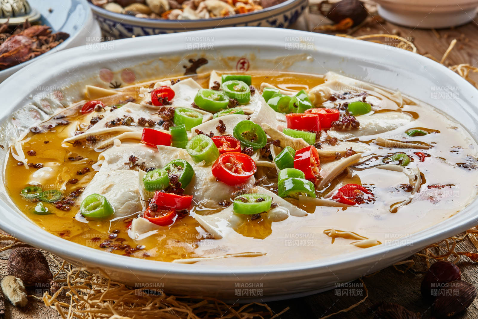 青瓷湯盆裝的酸湯黃喉擺放在陳舊木板上