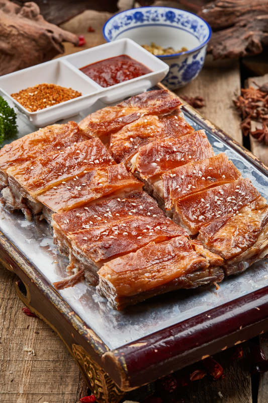 红色漆盘装的蒙古烤羊排摆放在樟木砧板上