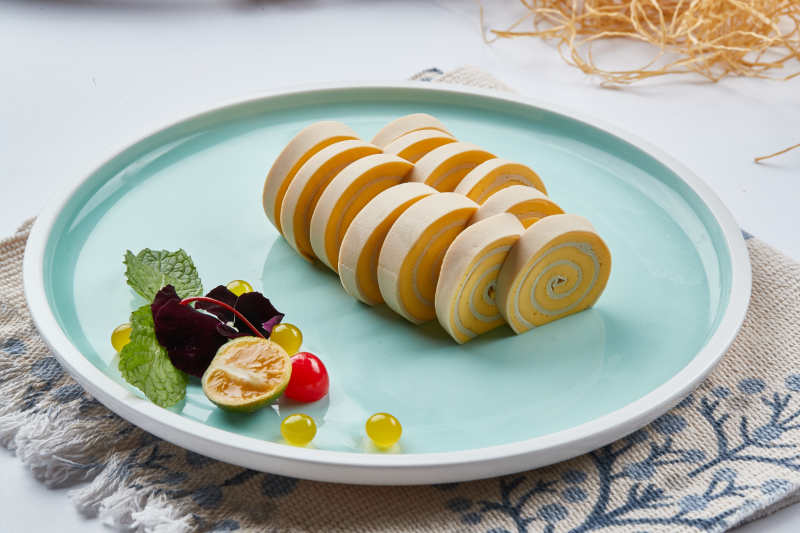 白色瓷盘组昂的豆腐皮熏肉卷切片